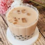 A glass of earl grey milk tea with ice and tapioca pearls boba.
