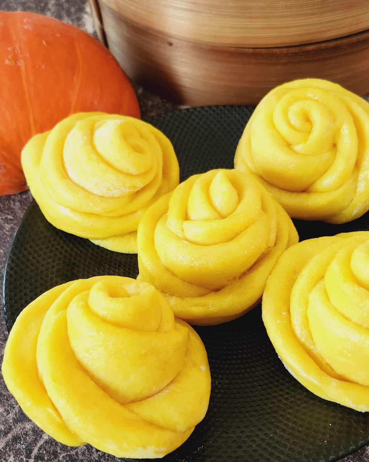 Rose-shaped pumpkin mantou on a black plate.
