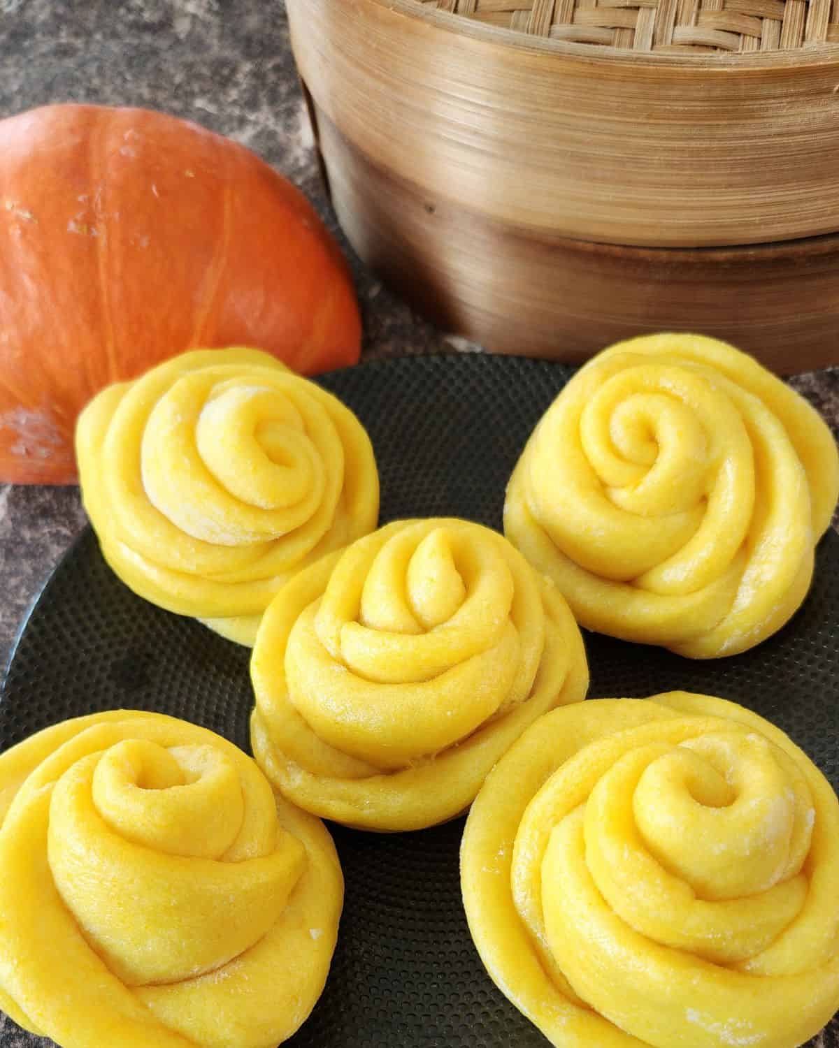 Rose-shaped pumpkin mantou on a black plate.