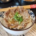 Steamed ground pork patty on top of a bowl of rice with chopsticks.