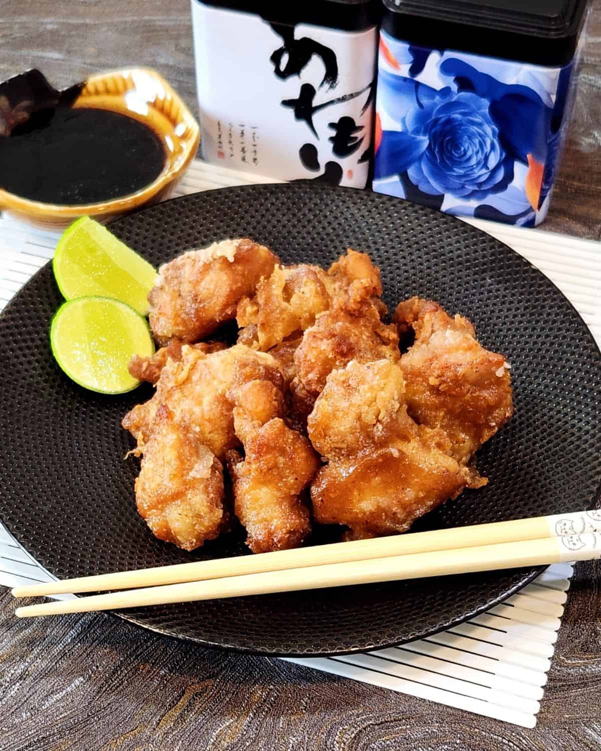 A plate of Chicken Karaage pieces with chopsticks and two slices of lime.