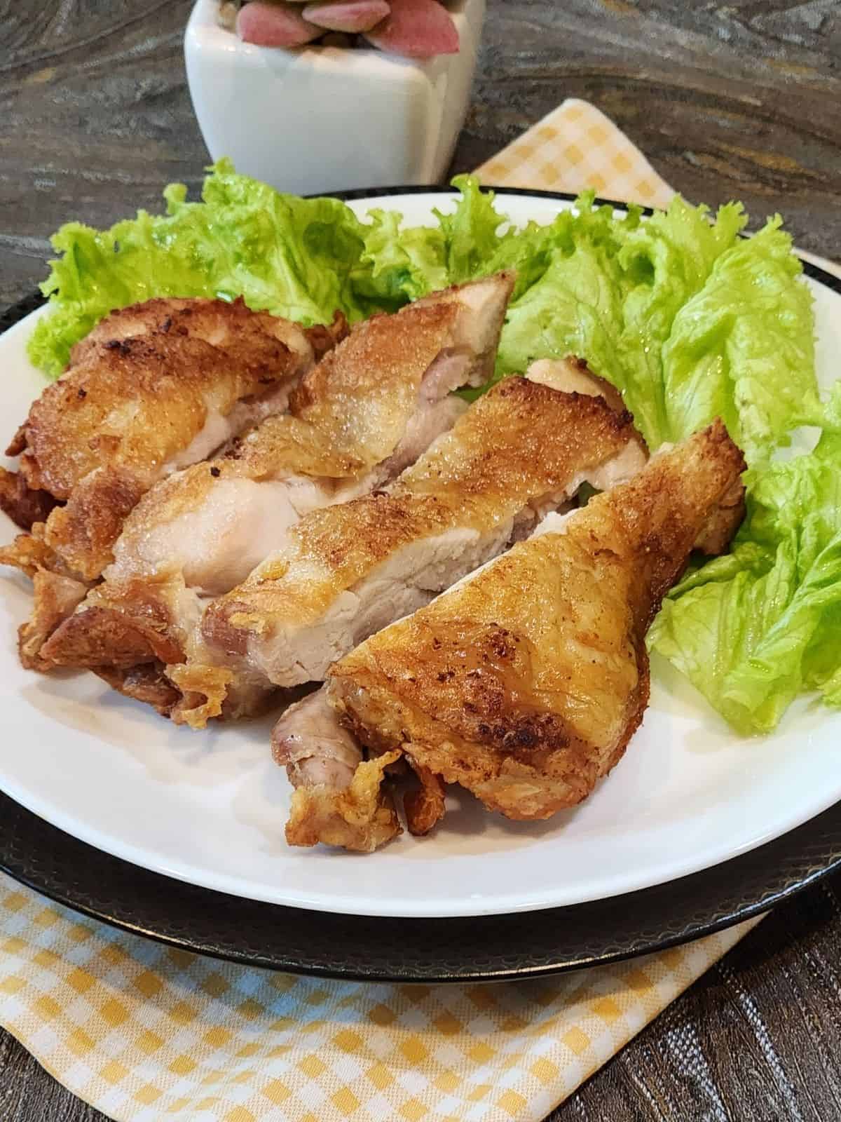 Flourless fried chicken slices on a white plate, garnished with lettuce.