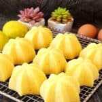 Mini Lemon Steamed Cakes on a cooling rack with small plants at the back.