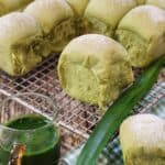 Pandan milk bread on a cooling rack and some pandan extract in a small cup.