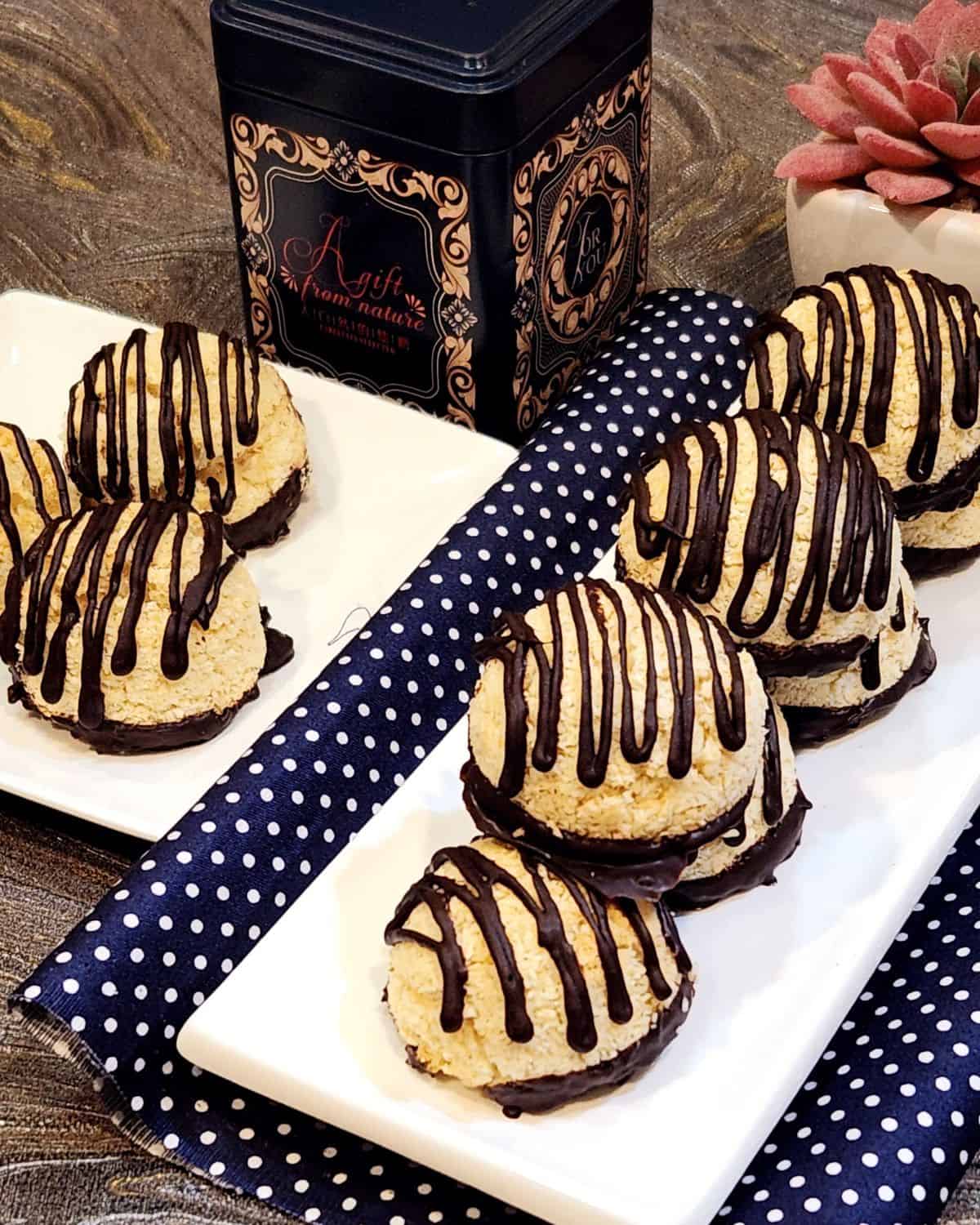 Two plates of coconut macaroon with chocolate on a granite table.