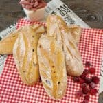 Cranberry Cream Cheese Bread on red and white cloth with some frozen cranberries.