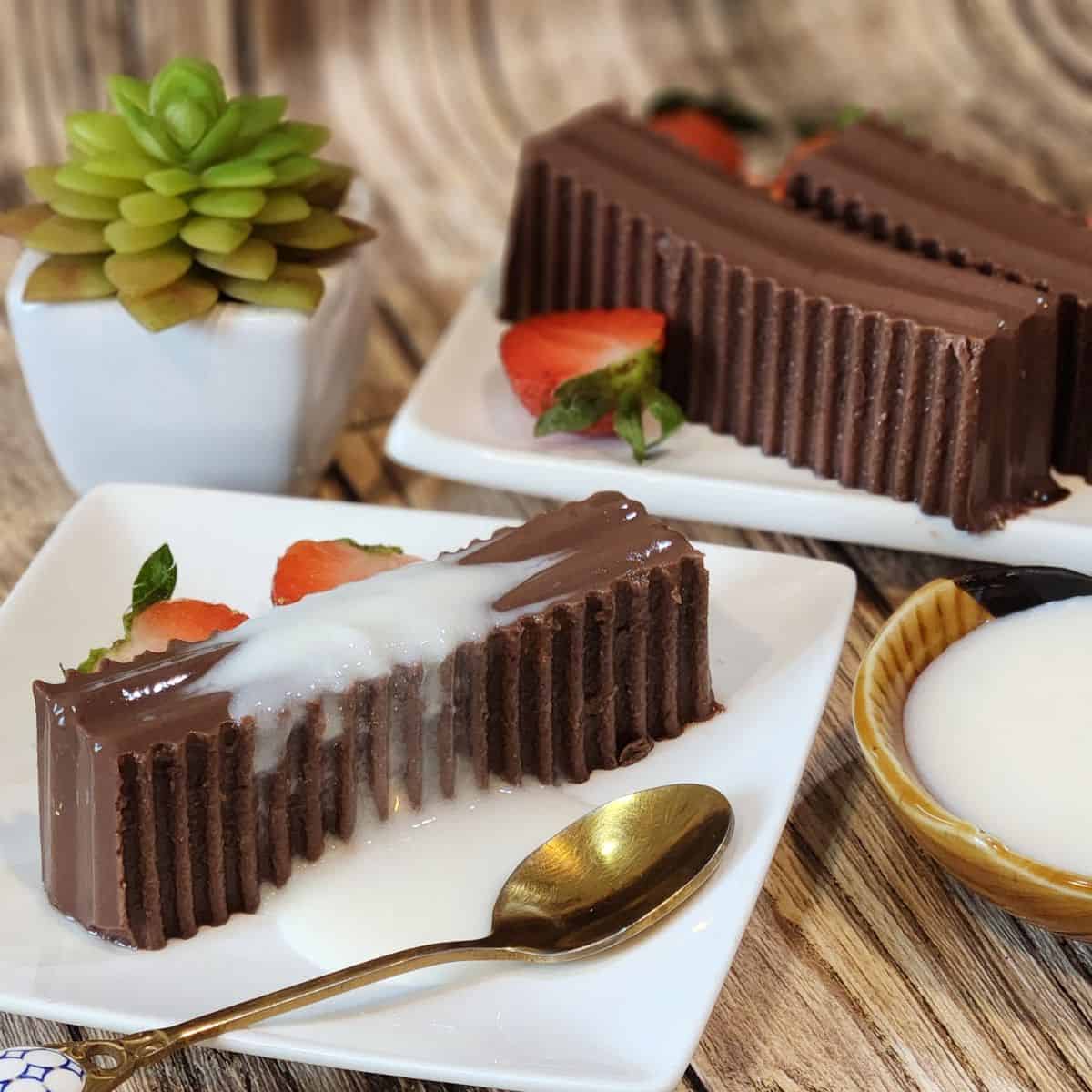 A plate of gluten free chocolate pudding with milk sauce, strawberries, and a spoon.
