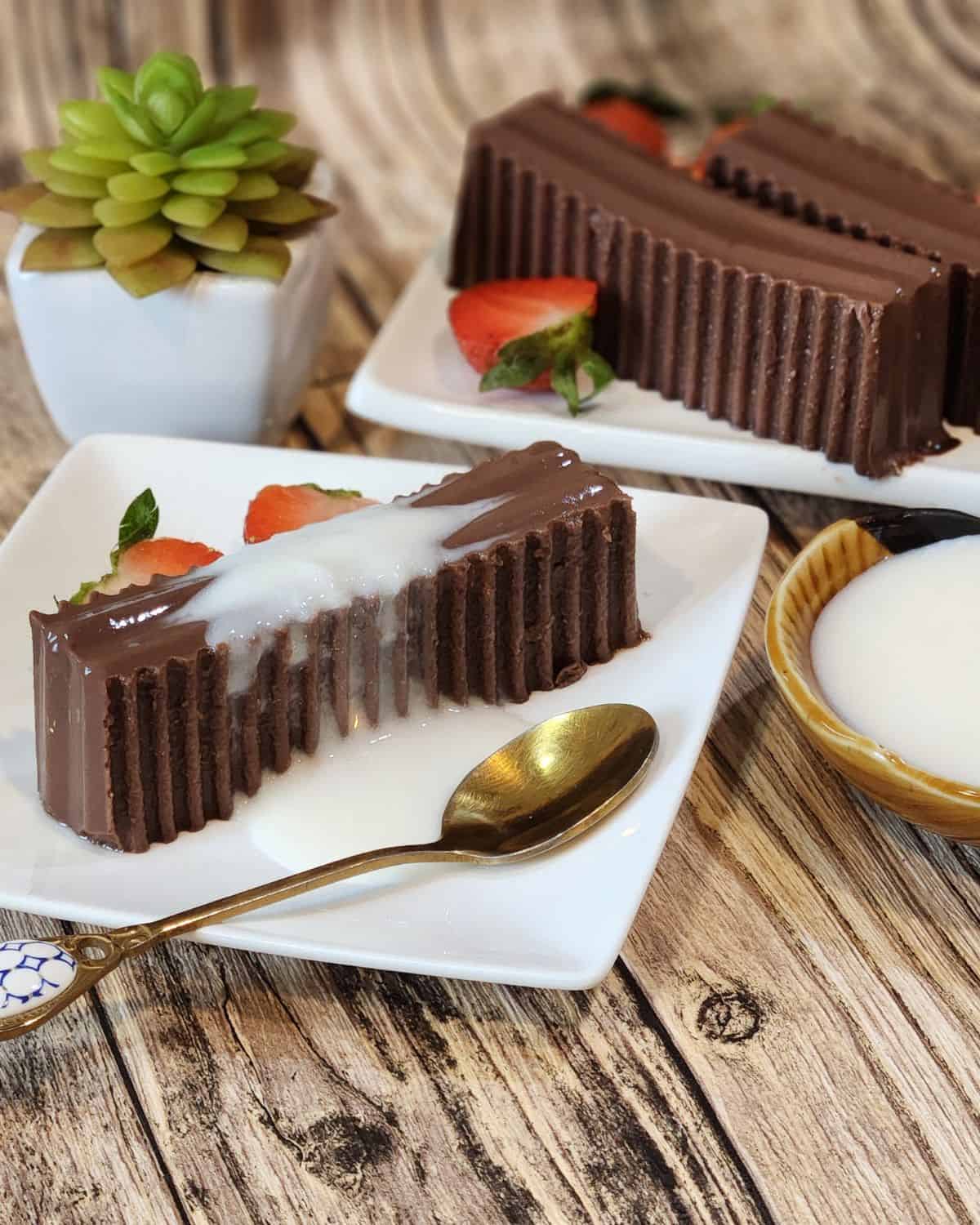 A plate of gluten free chocolate pudding with milk sauce, strawberries, and a spoon.