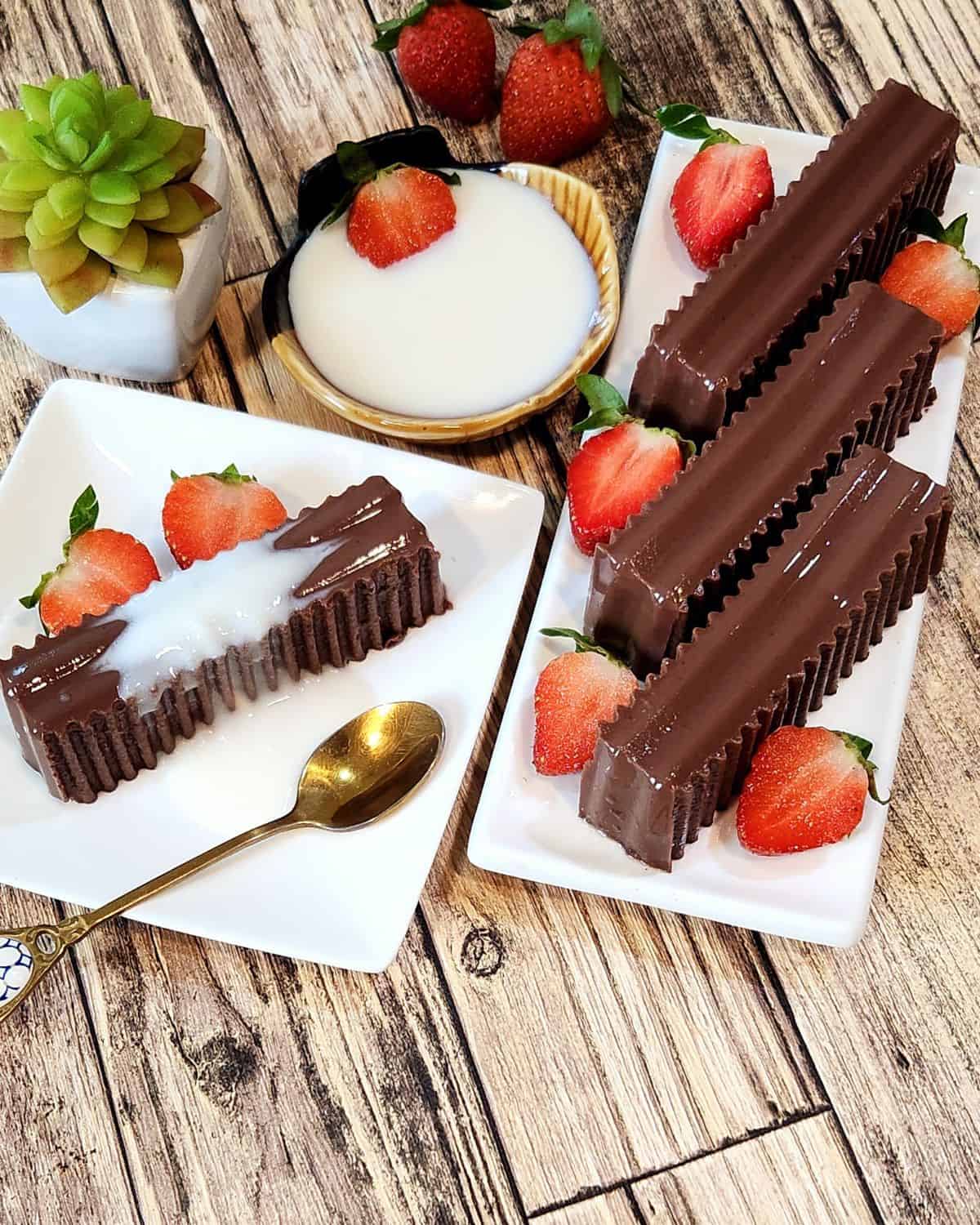 A plate of gluten free chocolate pudding with milk sauce, strawberries, and a spoon.