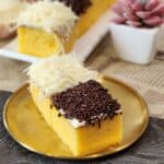 A golden plate of two mini cakes with cheese and chocolate toppings.