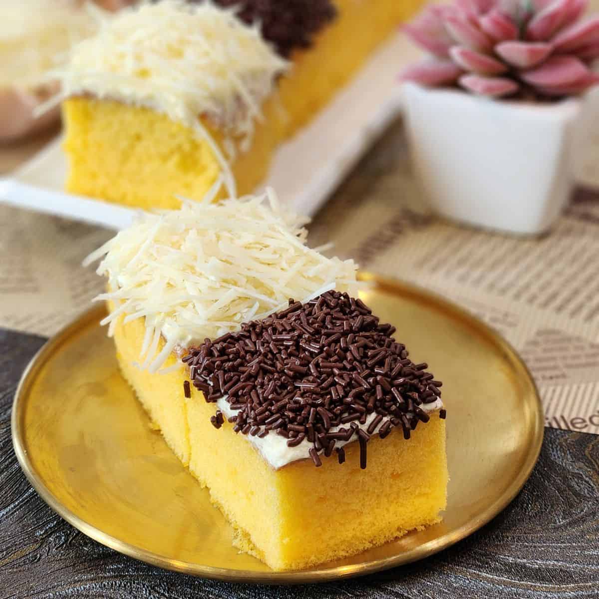 A golden plate of two mini cakes with cheese and chocolate toppings.