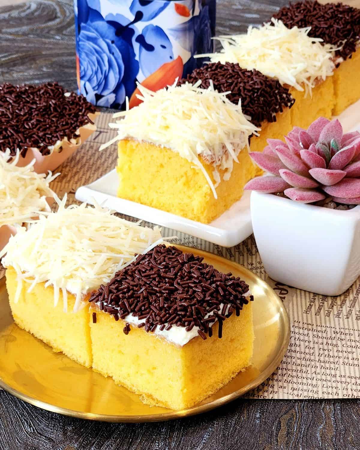A plate of yellow mini cakes with cheese and chocolate topping.