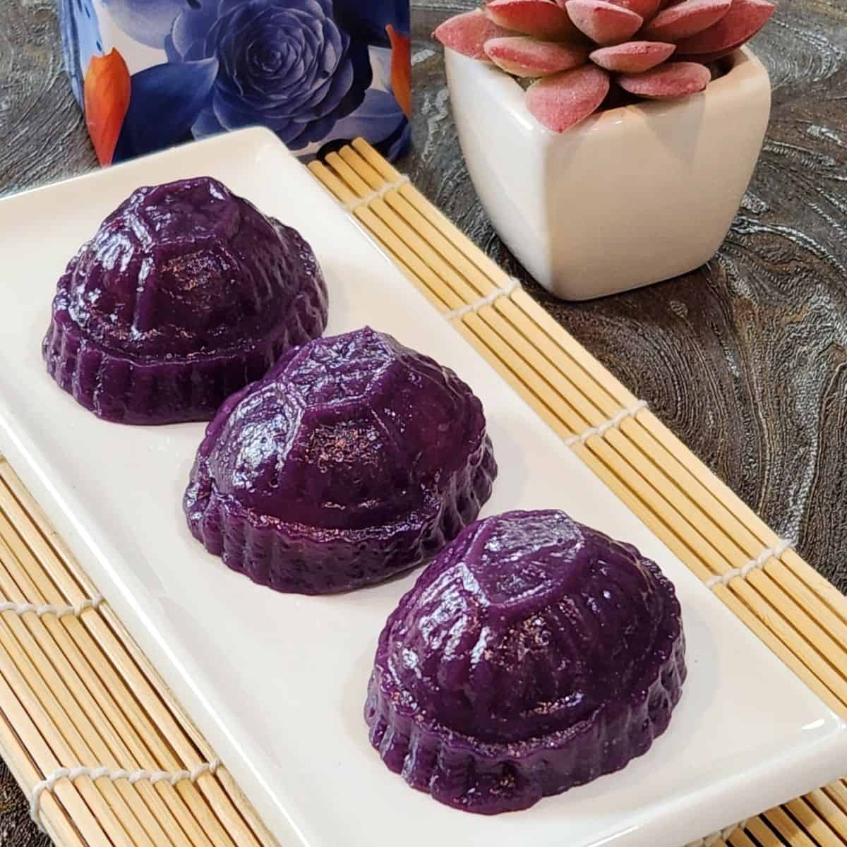 A plate of three angku kueh made of purple sweet potato.