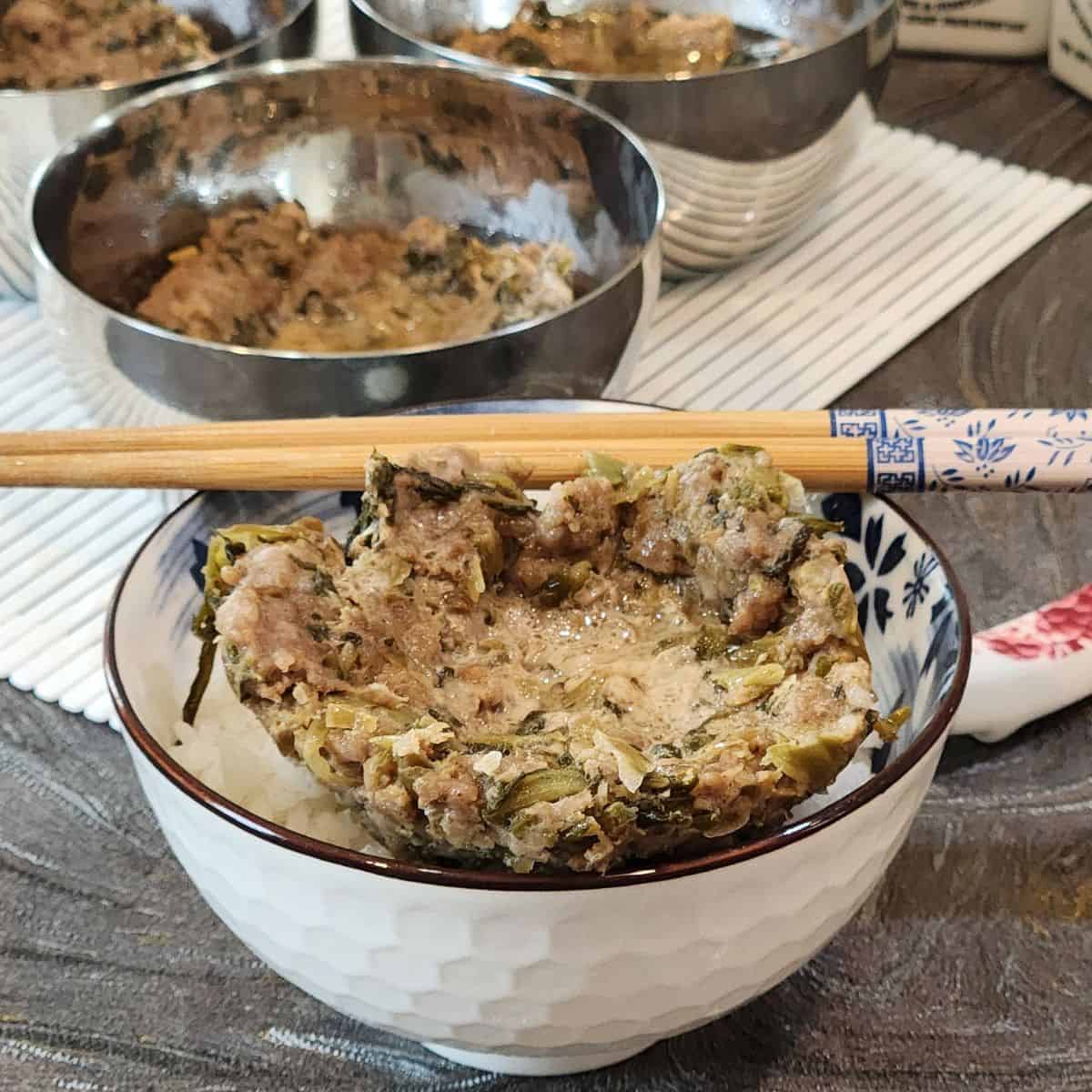 A bowl of rice with nyuk piang (steamed ground pork) and chopsticks.