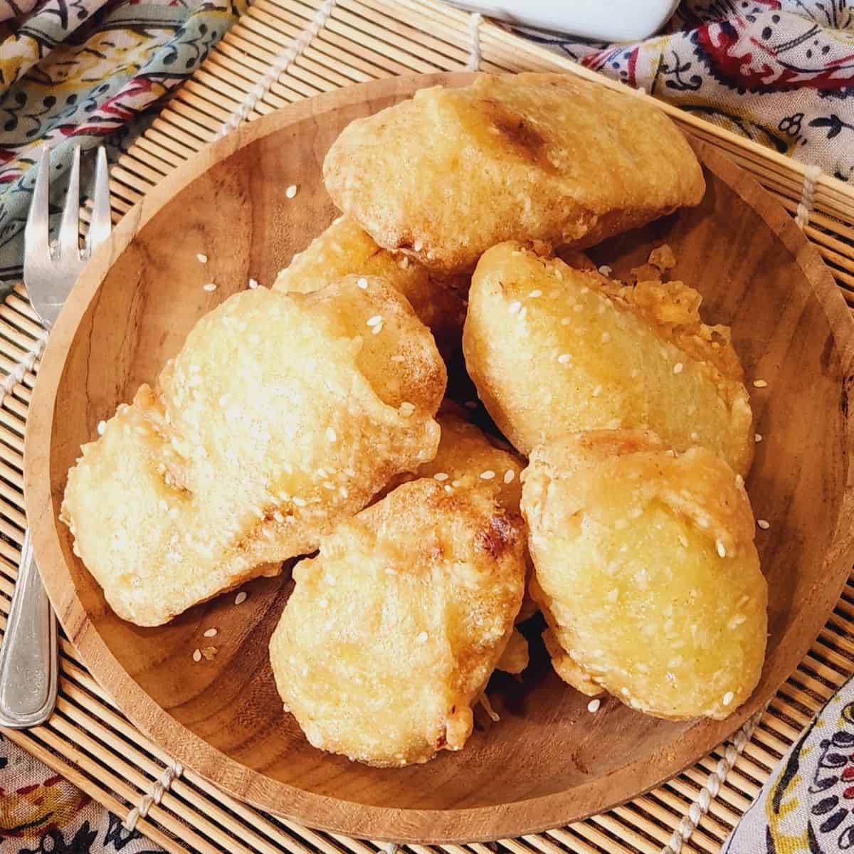 Several pisang goreng on a wooden plate.