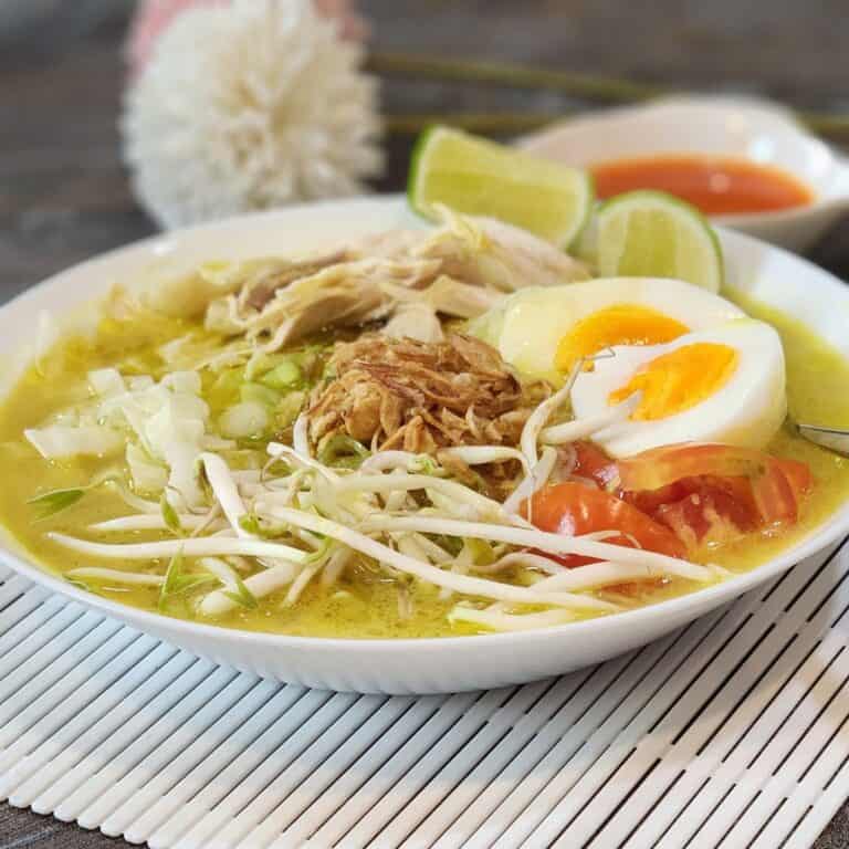 A bowl of Soto Ayam with bean sprouts and boiled eggs.