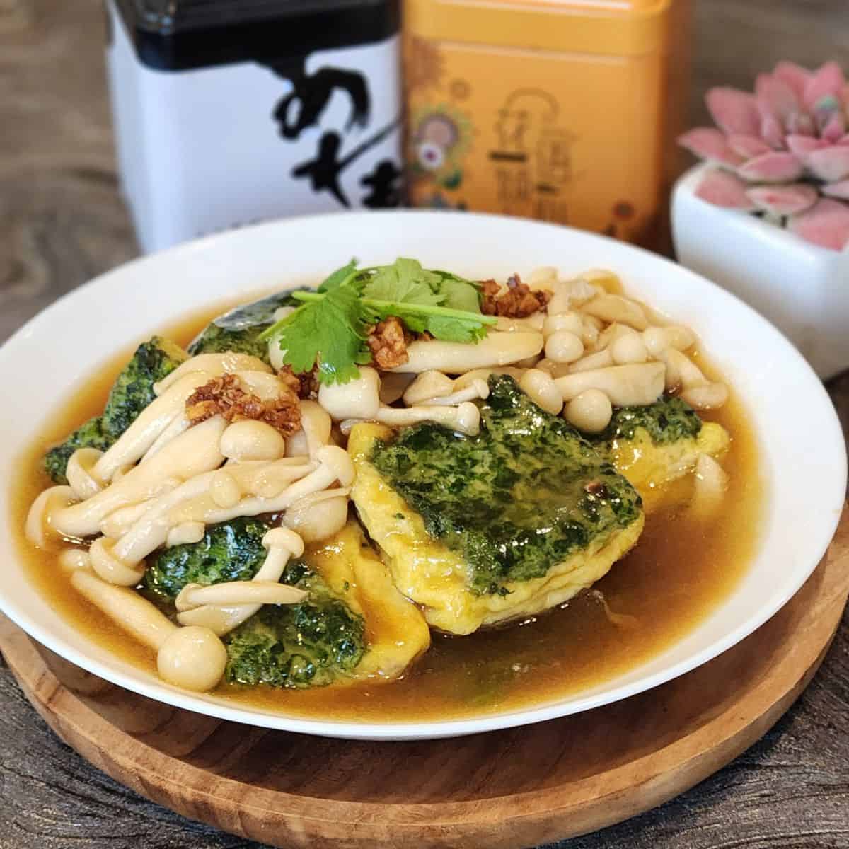 A plate of spinach tofu with shimeji mushrooms, garnished with coriander leaves.