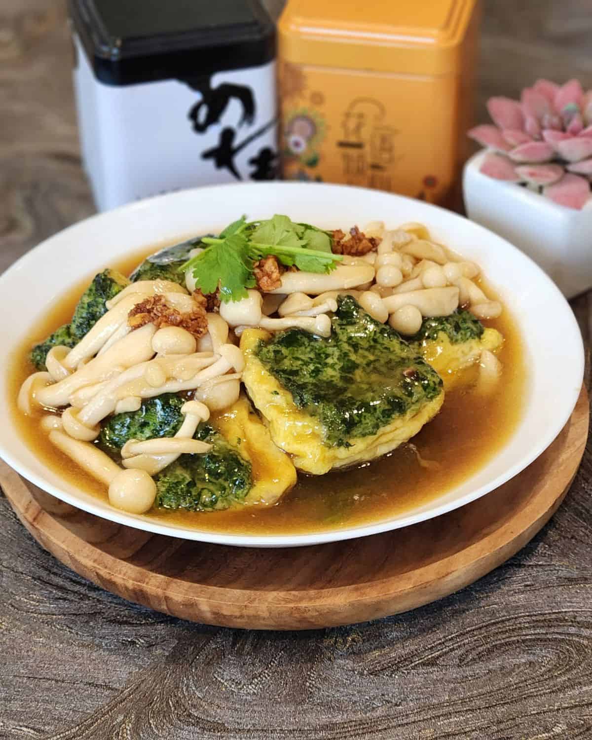 A plate of spinach tofu with shimeji mushrooms, garnished with coriander leaves.