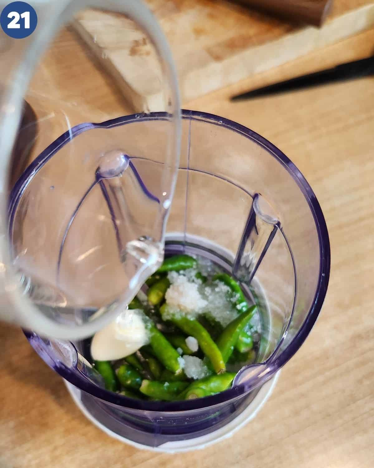 Putting the green chili and seasoning in a food processor.
