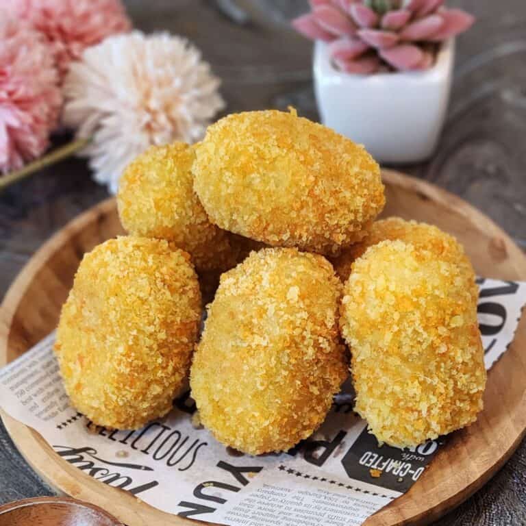 A few krokets or Dutch croquettes on a parchment paper and wooden plate.