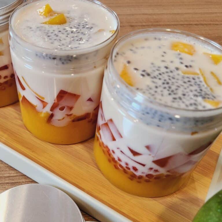 Jars of mango pomelo sago on a wooden tray.