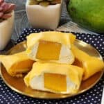 A stack of sliced mango pancakes on a golden plate with several more on the side.