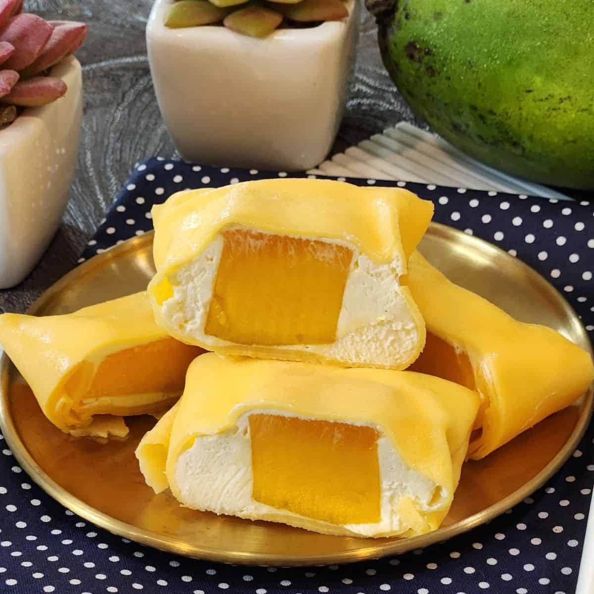 A stack of sliced mango pancakes on a golden plate with several more on the side.